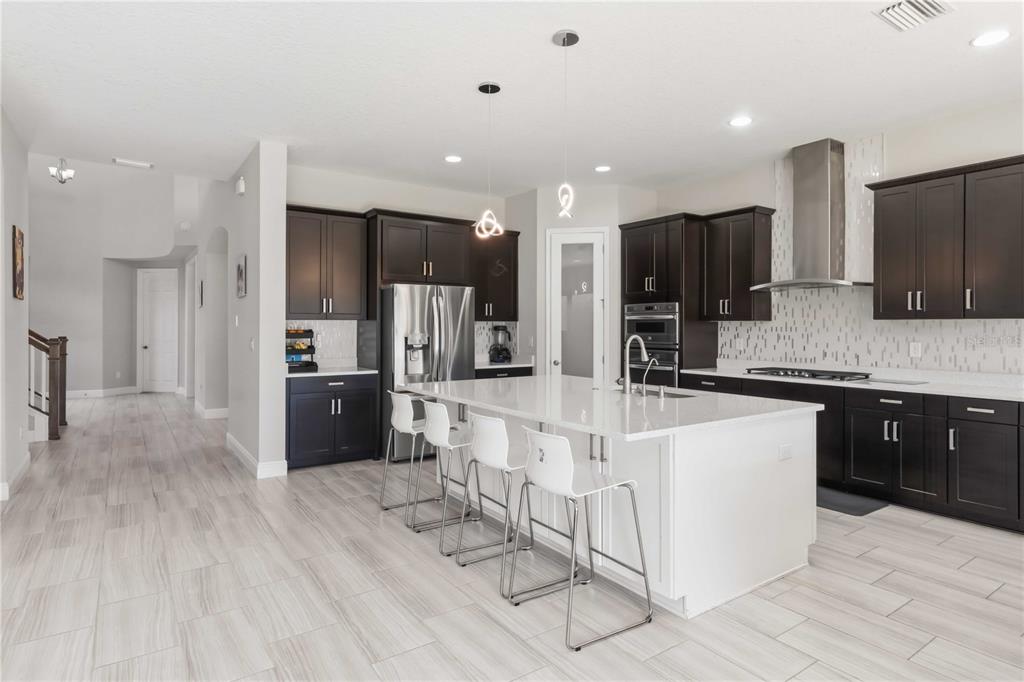 A modern kitchen features dark wood cabinetry, a white quartz island, and light tile flooring — 805 VISCOUNT STREET, BRANDON, FL