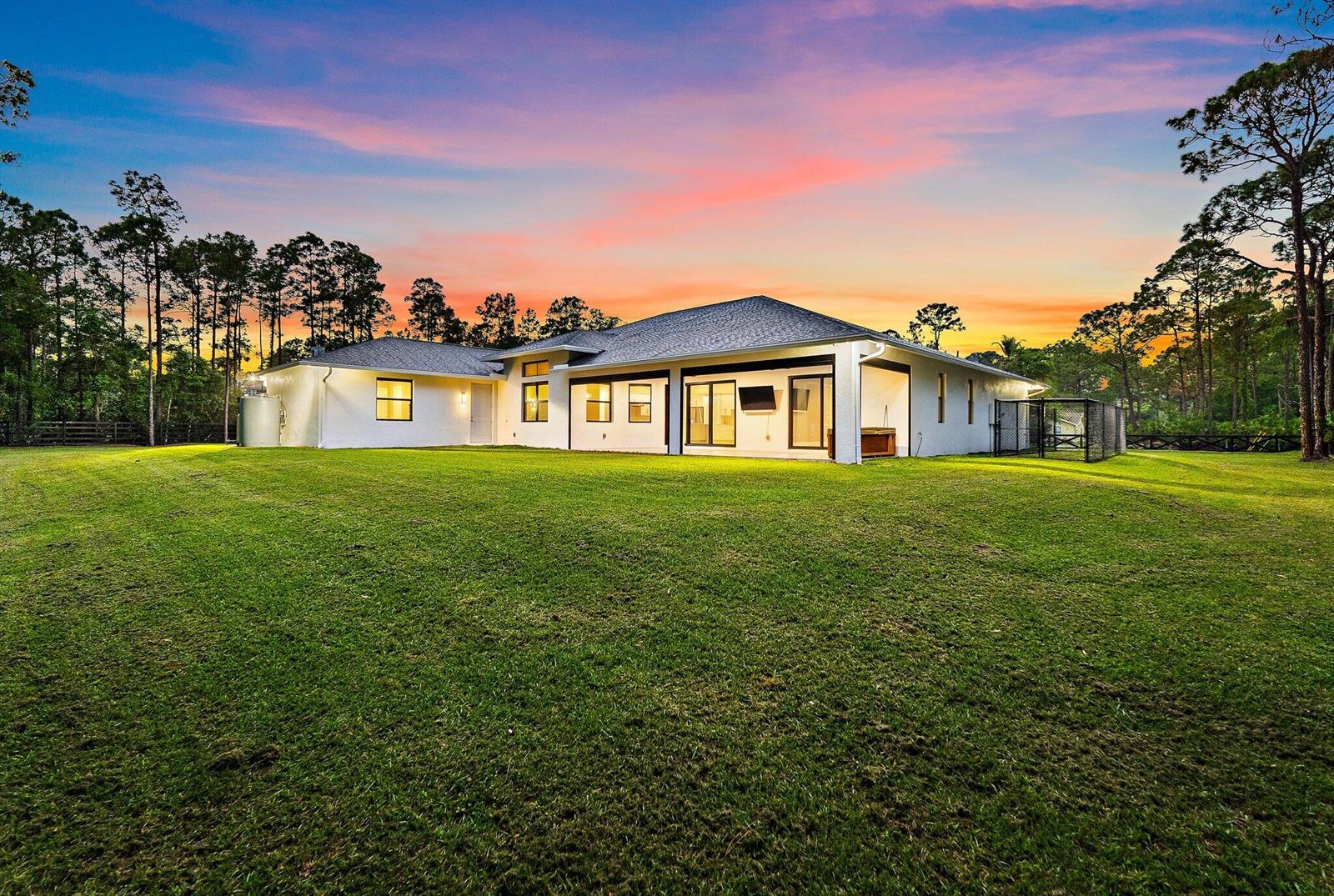 A white single-story house with a large lawn under a colorful sunset sky — 16096 132nd Terrace N, Jupiter FL 33478, JUPITER, FL