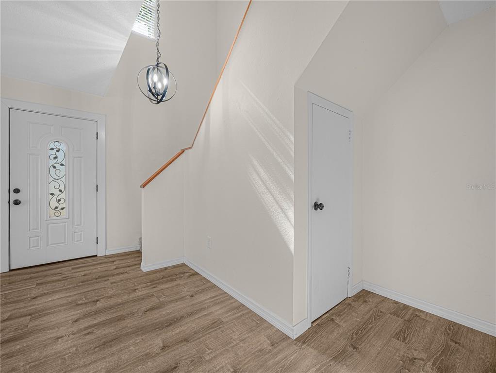 An entryway features wood-look flooring, a white door, a pendant light, and a closet door — 3573 RAINTREE CIRCLE, LAKELAND, FL