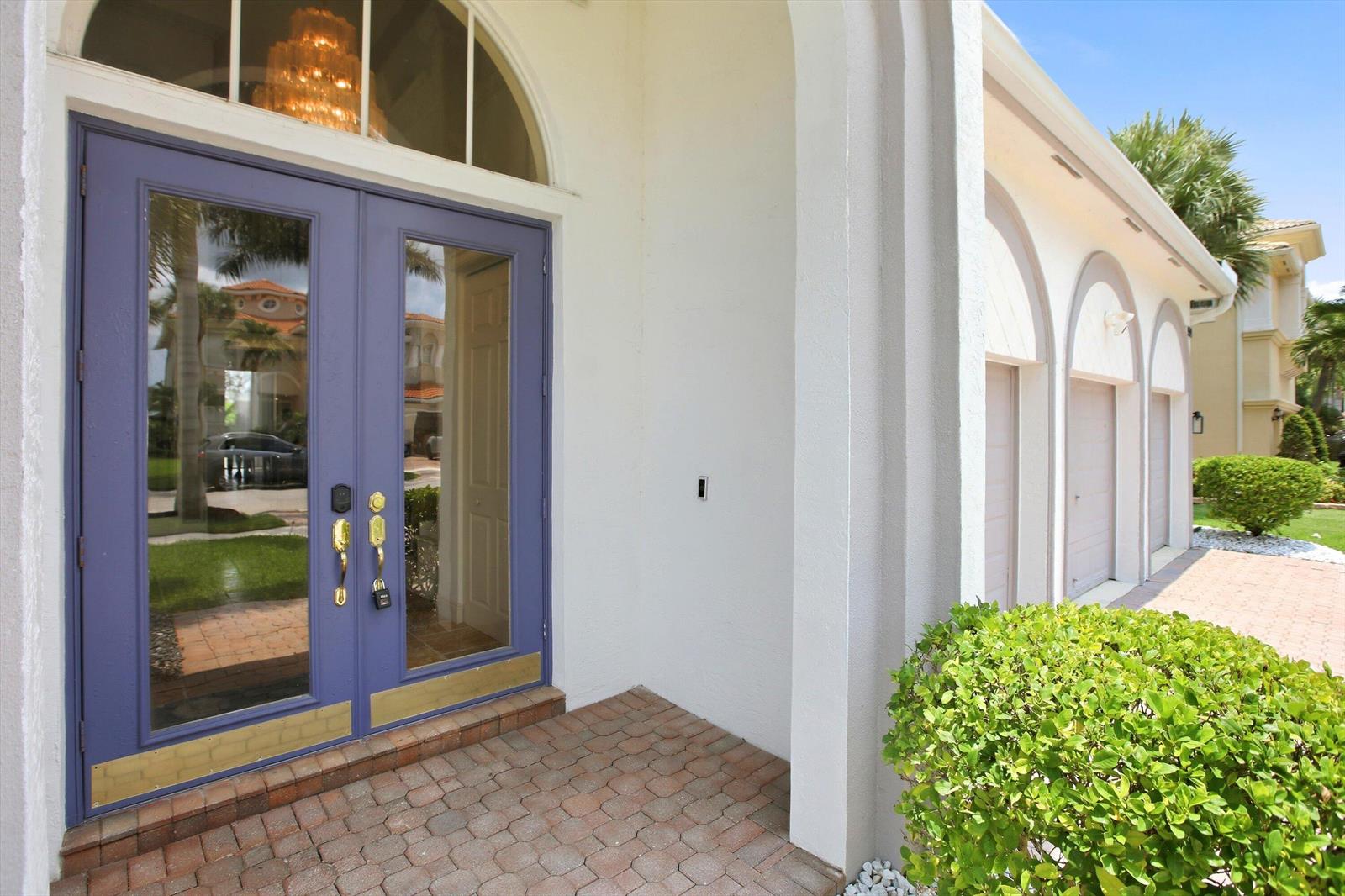 A purple double front door with glass panels sits under an arched entryway — 9599 Shepard Place, Wellington FL 33414, WELLINGTON, FL