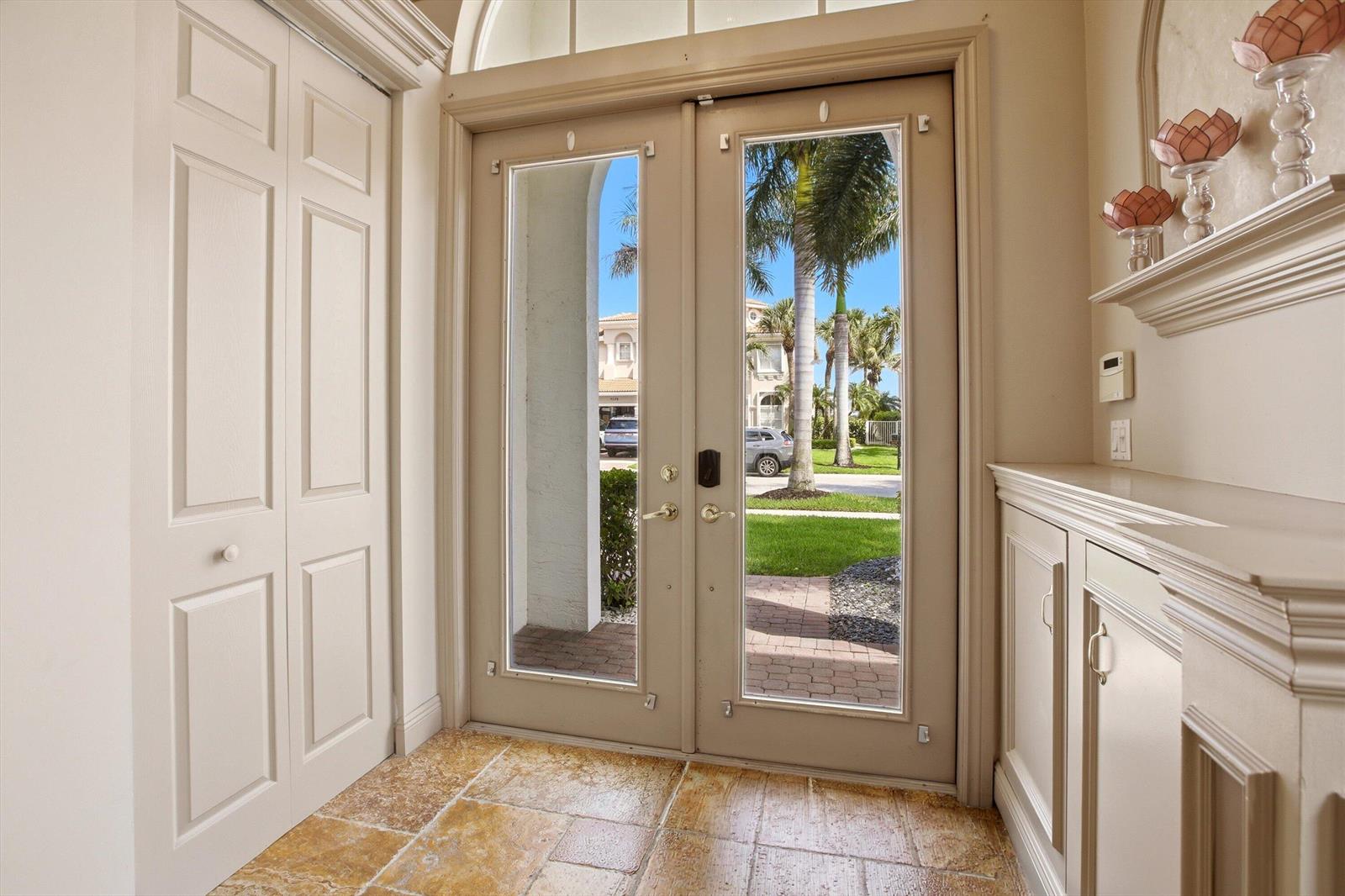 An entryway features double glass doors, stone tile flooring, and built-in cabinetry — 9599 Shepard Place, Wellington FL 33414, WELLINGTON, FL