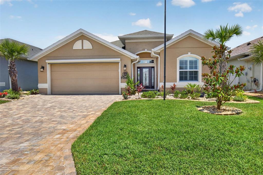A single-story tan house with a paved driveway, a two-car garage, and a front lawn — 37 LAGOON WAY, PALM COAST, FL