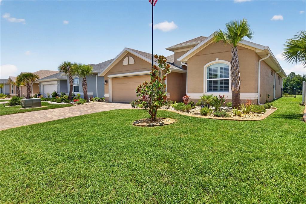 A tan single-story house with a paved driveway, palm trees, and a manicured lawn — 37 LAGOON WAY, PALM COAST, FL