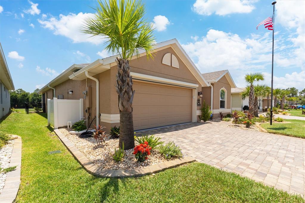 A tan house with a two-car garage, a paved driveway, and a palm tree out front — 37 LAGOON WAY, PALM COAST, FL