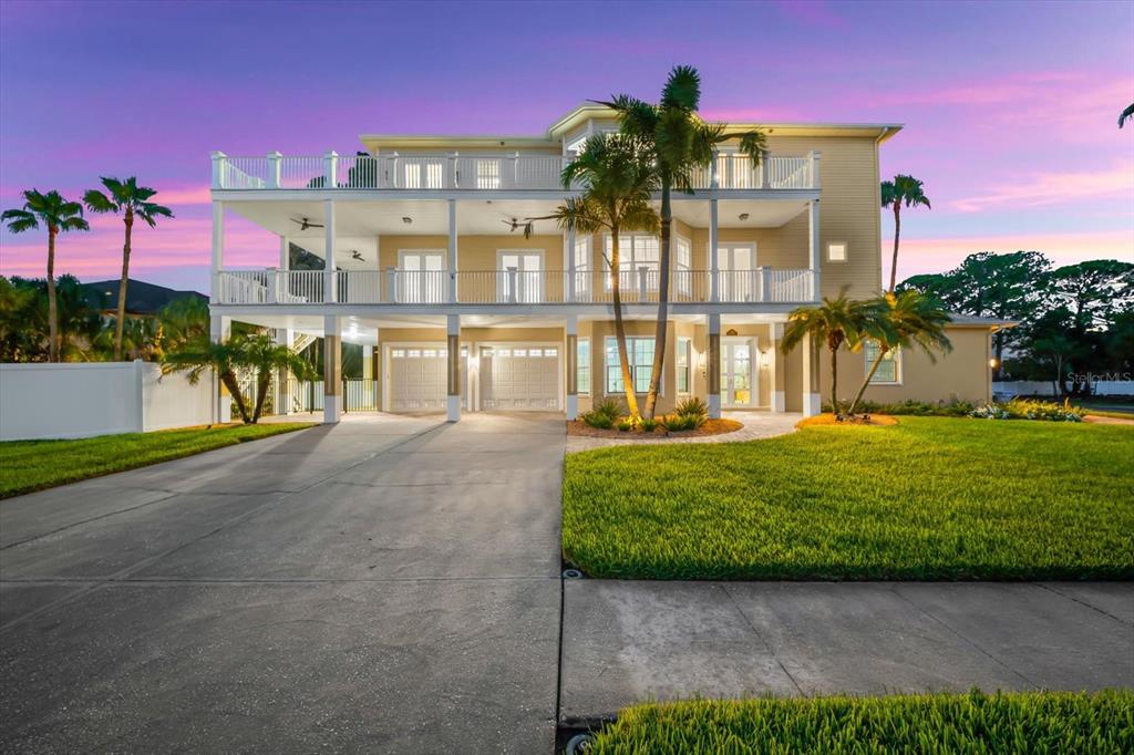 A three-story house with a concrete driveway, two-car garage, and two levels of wrap-around balconies — 1700 OYSTER POINT WAY, PALM HARBOR, FL