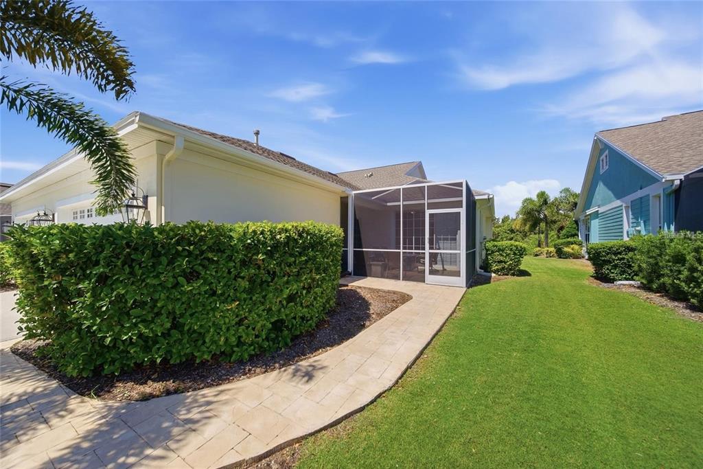 A paved walkway leads to a screened-in patio attached to the side of a house — 5610 GOLDEN ISLES DRIVE, APOLLO BEACH, FL