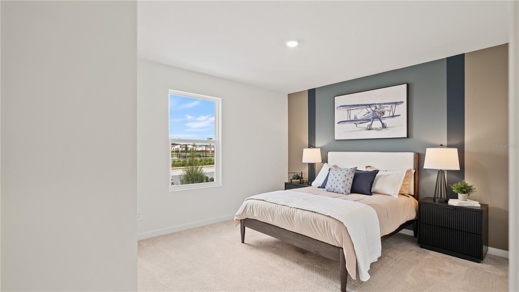 A bedroom features a bed with a blue and tan accent wall and a window — 6105 SWAMP BAY DRIVE, EDGEWATER, FL