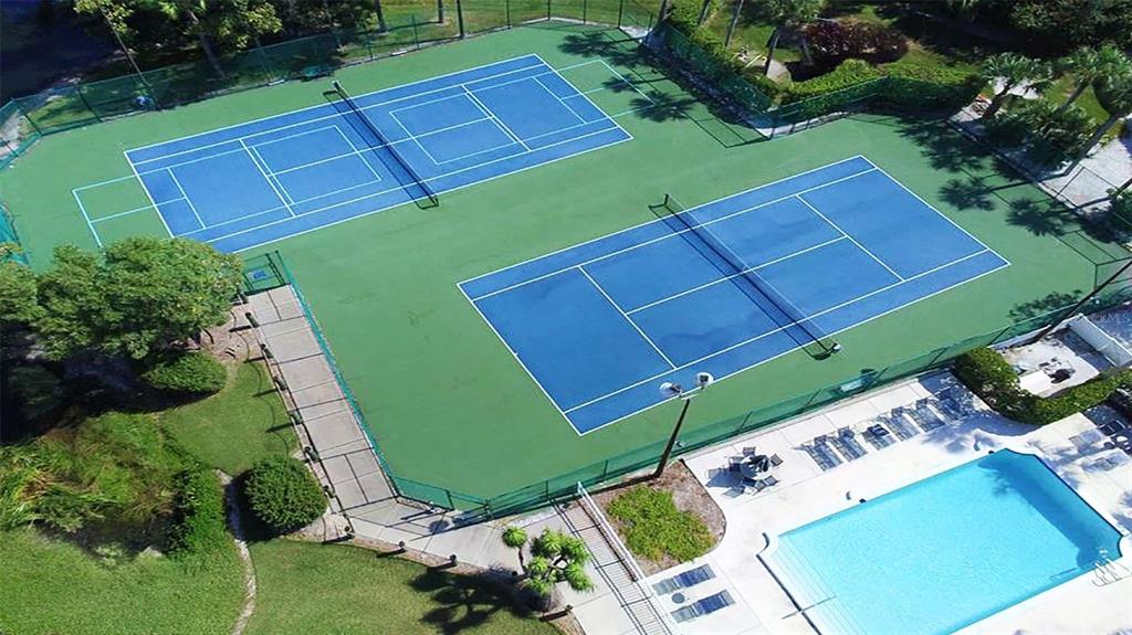 An aerial view shows two blue tennis courts next to a rectangular swimming pool — 1366 SIESTA BAYSIDE DRIVE UNIT 1366-F, SARASOTA, FL