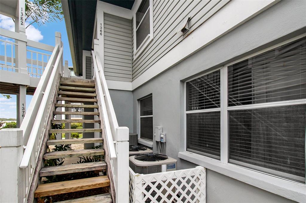 An exterior view shows a wooden staircase leading to upper units beside a gray building — 1366 SIESTA BAYSIDE DRIVE UNIT 1366-F, SARASOTA, FL