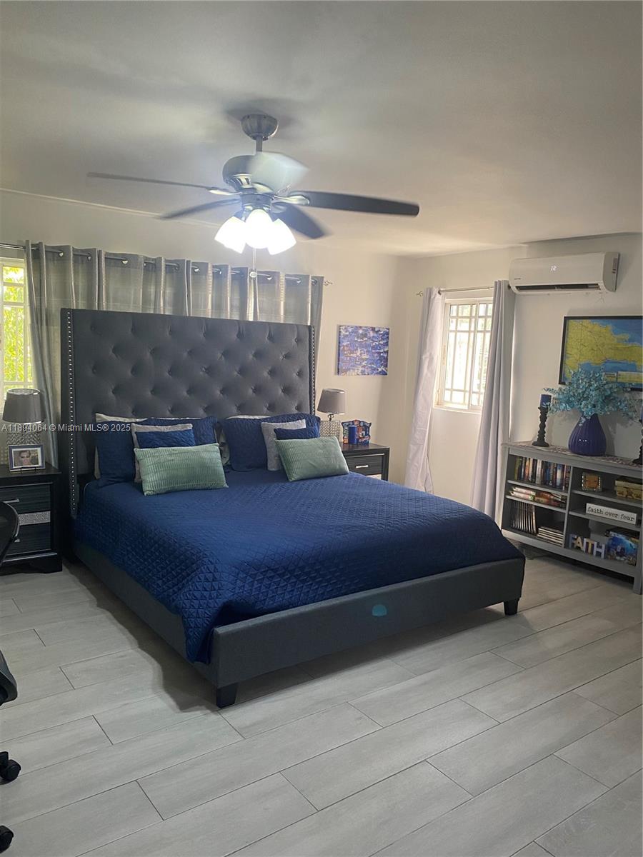 A bedroom features a tufted gray headboard, blue bedding, a ceiling fan, and light flooring — 6 CALLE 29 ESTE, NY 10133, NY