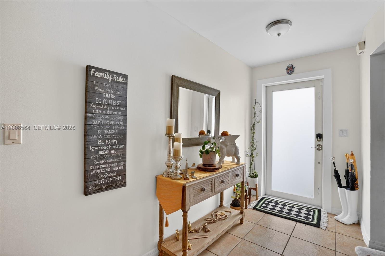 An entryway features a console table, a wall-mounted family rules sign, and a glass-paneled door — 8330 SW 154th Ave # 35, Miami FL 33193, MIAMI, FL