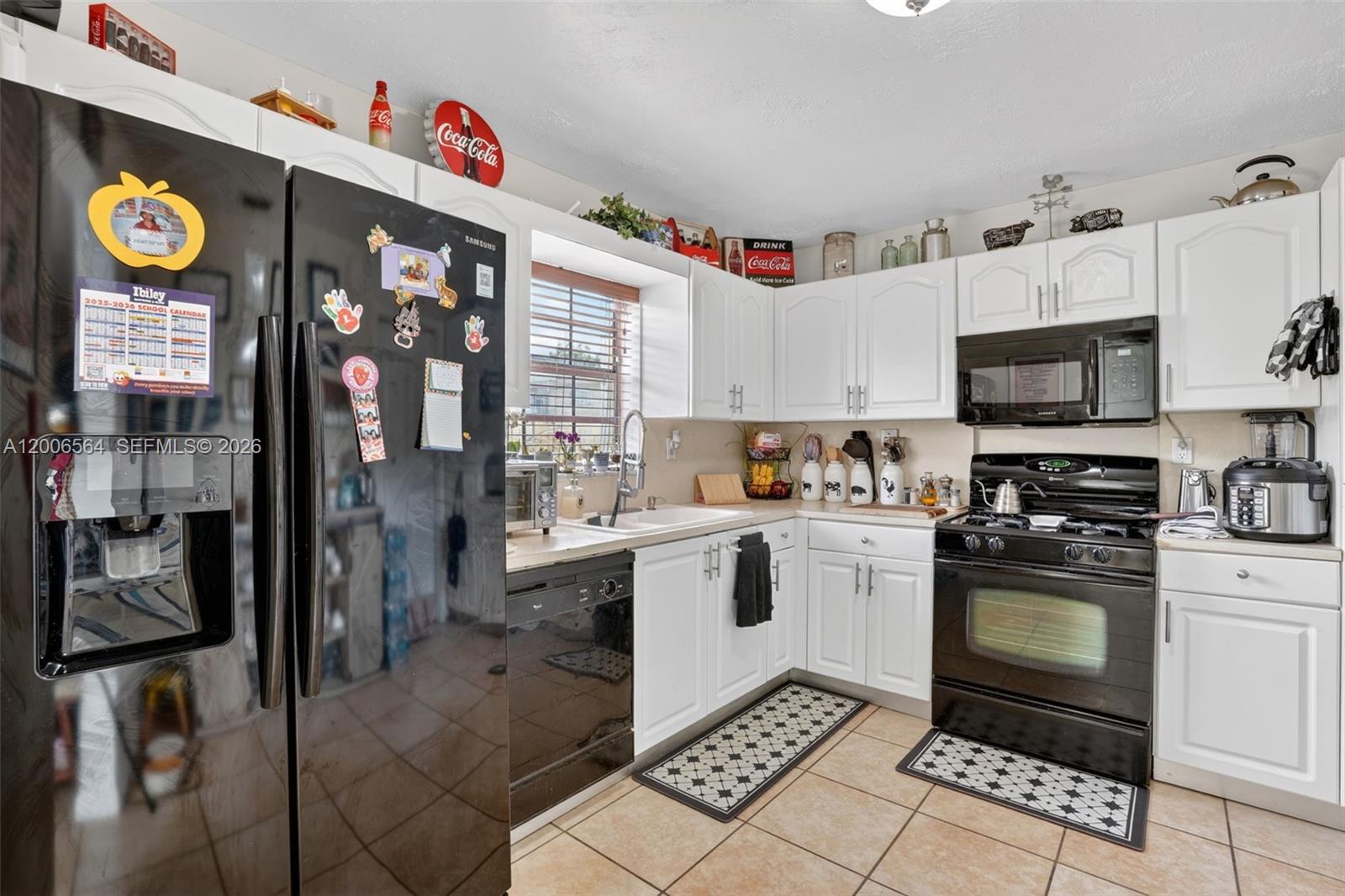 A kitchen features white cabinetry, black appliances, tile flooring, and a window above the sink — 8330 SW 154th Ave # 35, Miami FL 33193, MIAMI, FL