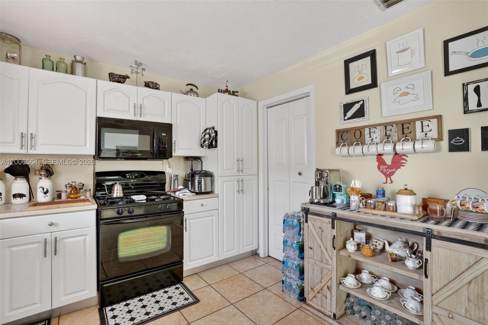 A kitchen features white cabinets, black appliances, tile flooring, and a rustic coffee station — 8330 SW 154th Ave # 35, Miami FL 33193, MIAMI, FL