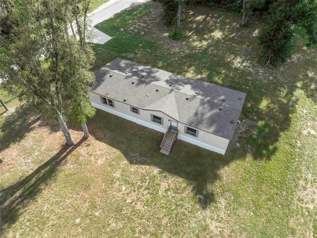 An aerial view shows a single-story manufactured home with a shingled roof and wooden steps — 968 CR222 ROAD, OXFORD, FL