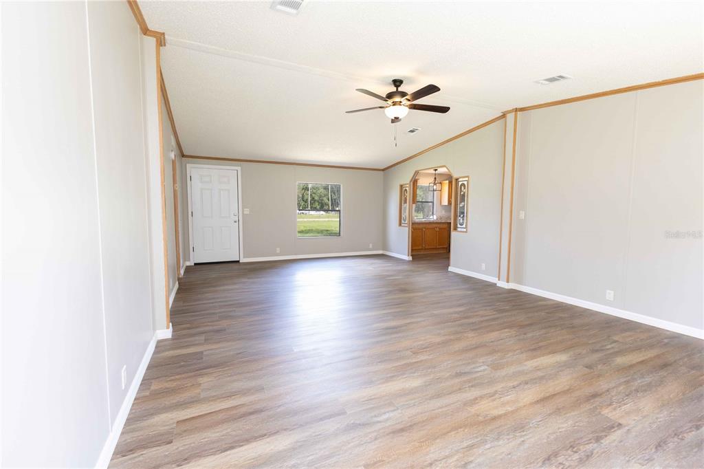 An open-concept living room with light gray walls, wood-look flooring, and a ceiling fan — 968 CR222 ROAD, OXFORD, FL