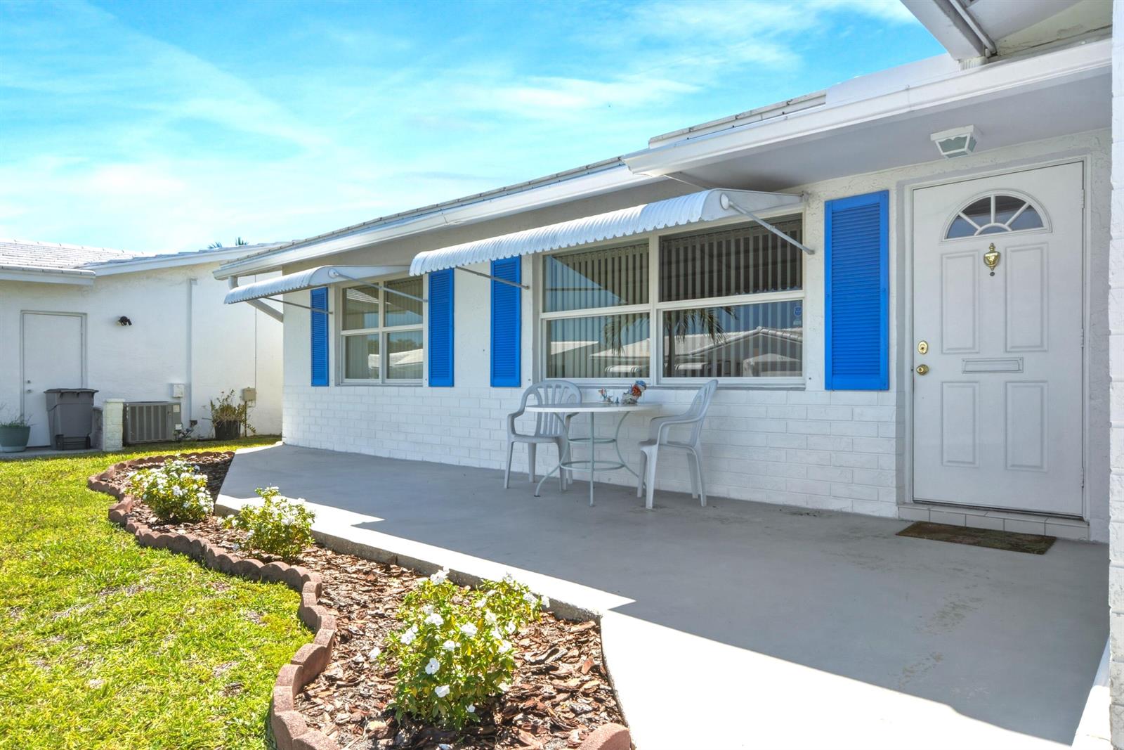 A white house with blue shutters, a concrete patio, and a small garden bed — 2108 SW 15th Street, Boynton Beach FL 33426, BOYNTON BEACH, FL