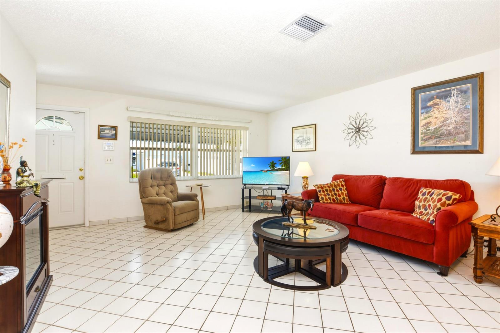 A living room features white tiled floors, a red sofa, a recliner, and a television — 2108 SW 15th Street, Boynton Beach FL 33426, BOYNTON BEACH, FL