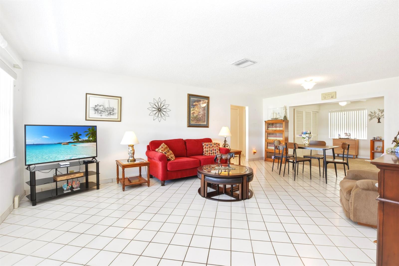 A living room with white tile floors, a red sofa, and a dining area beyond — 2108 SW 15th Street, Boynton Beach FL 33426, BOYNTON BEACH, FL