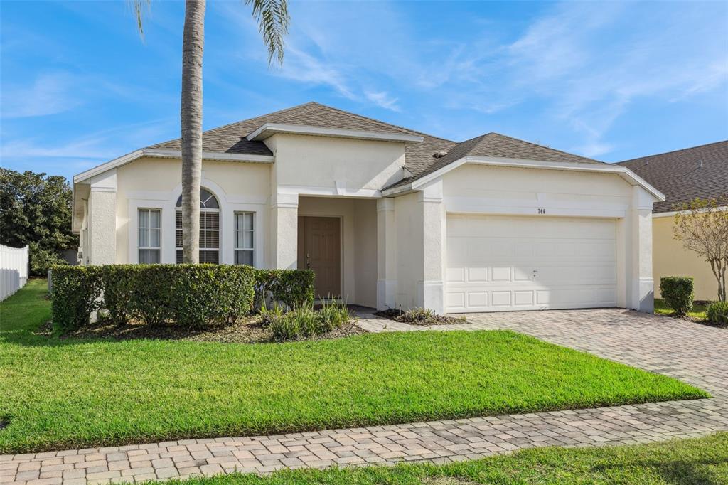 A single-story house with a beige stucco exterior, a two-car garage, and a palm tree — 746 KILDRUMMY DRIVE, DAVENPORT, FL
