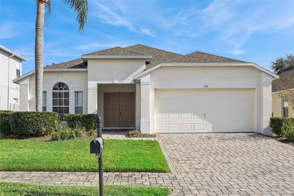 A single-story house with a beige stucco exterior, a two-car garage, and a paved driveway — 746 KILDRUMMY DRIVE, DAVENPORT, FL