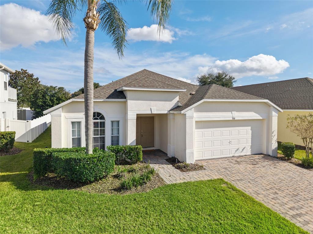A single-story house with a beige stucco exterior, a two-car garage, and a palm tree — 746 KILDRUMMY DRIVE, DAVENPORT, FL