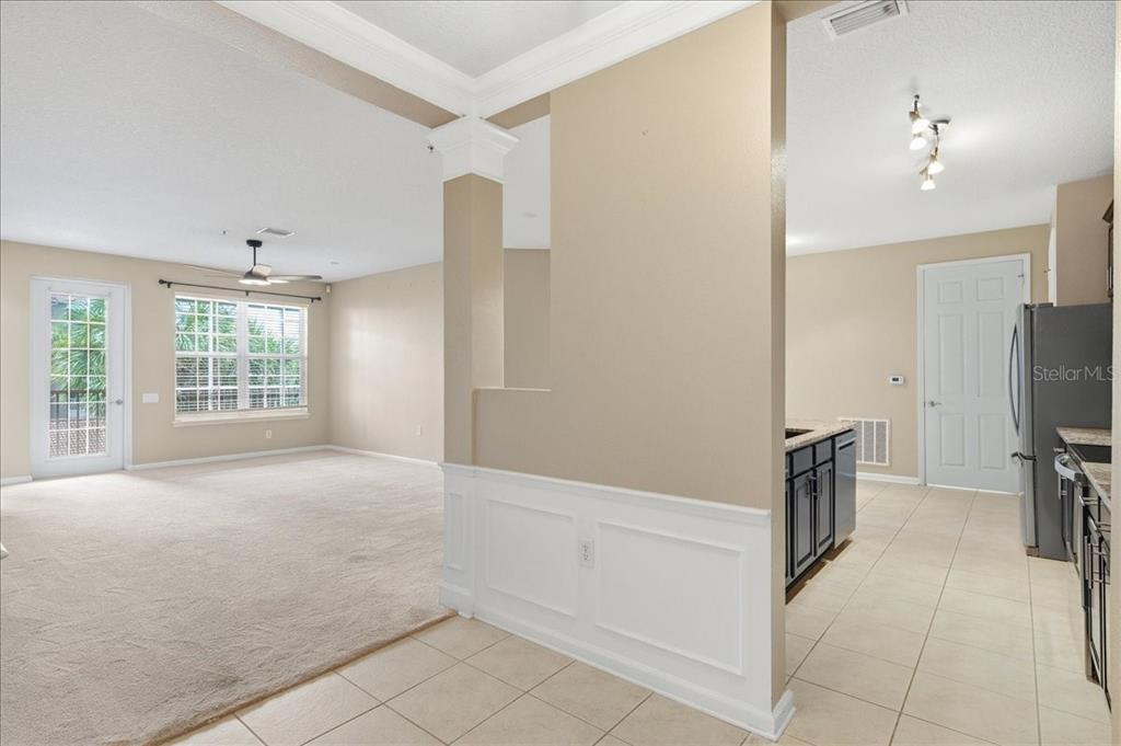 A view from a tiled kitchen area looking into a carpeted living room with windows — 7903 SEMINOLE BOULEVARD UNIT 2305, SEMINOLE, FL