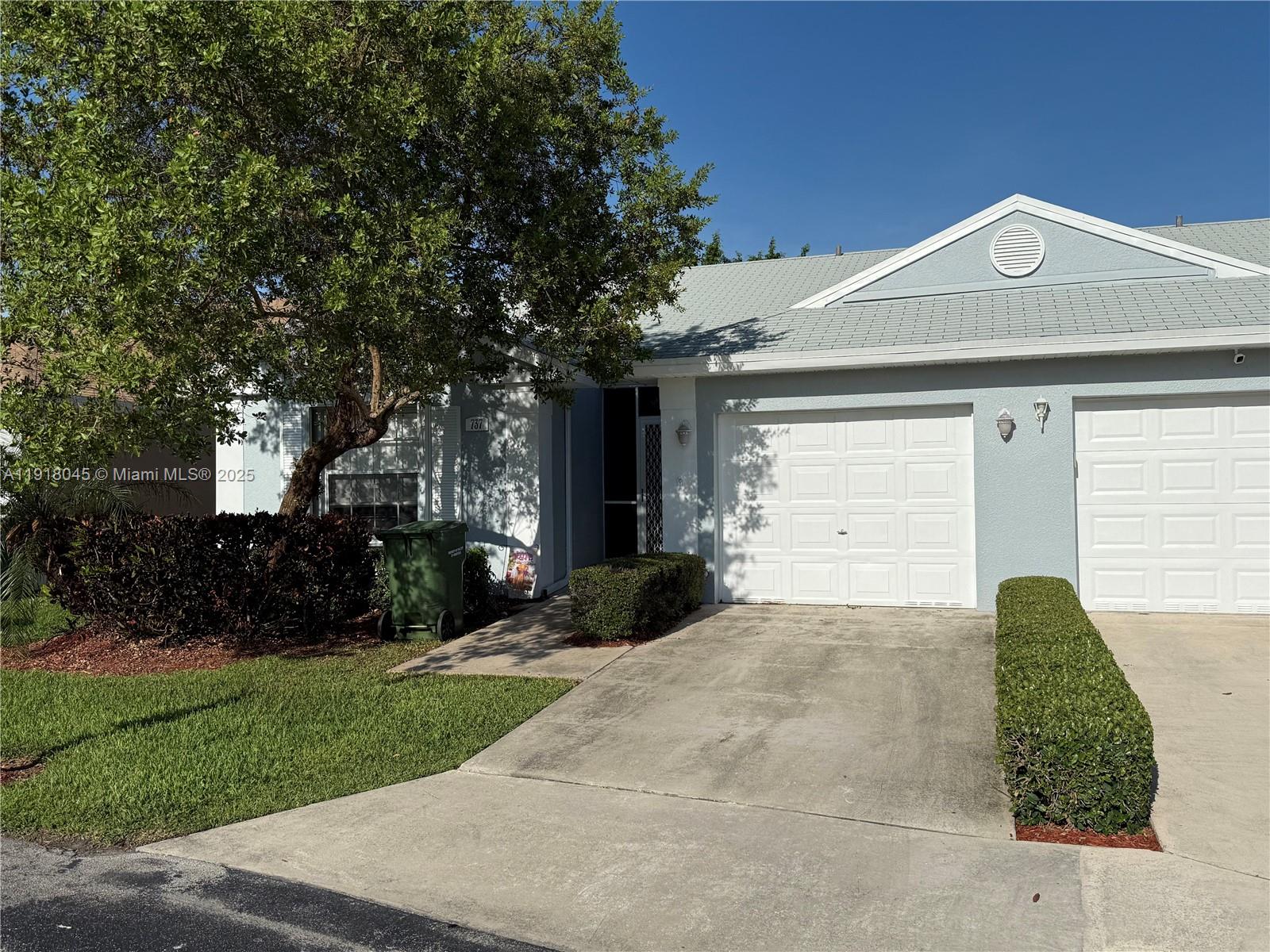 A light blue single-story house features a two-car garage and a manicured front hedge — 737 SE 22nd Dr, Homestead FL 33033, HOMESTEAD, FL