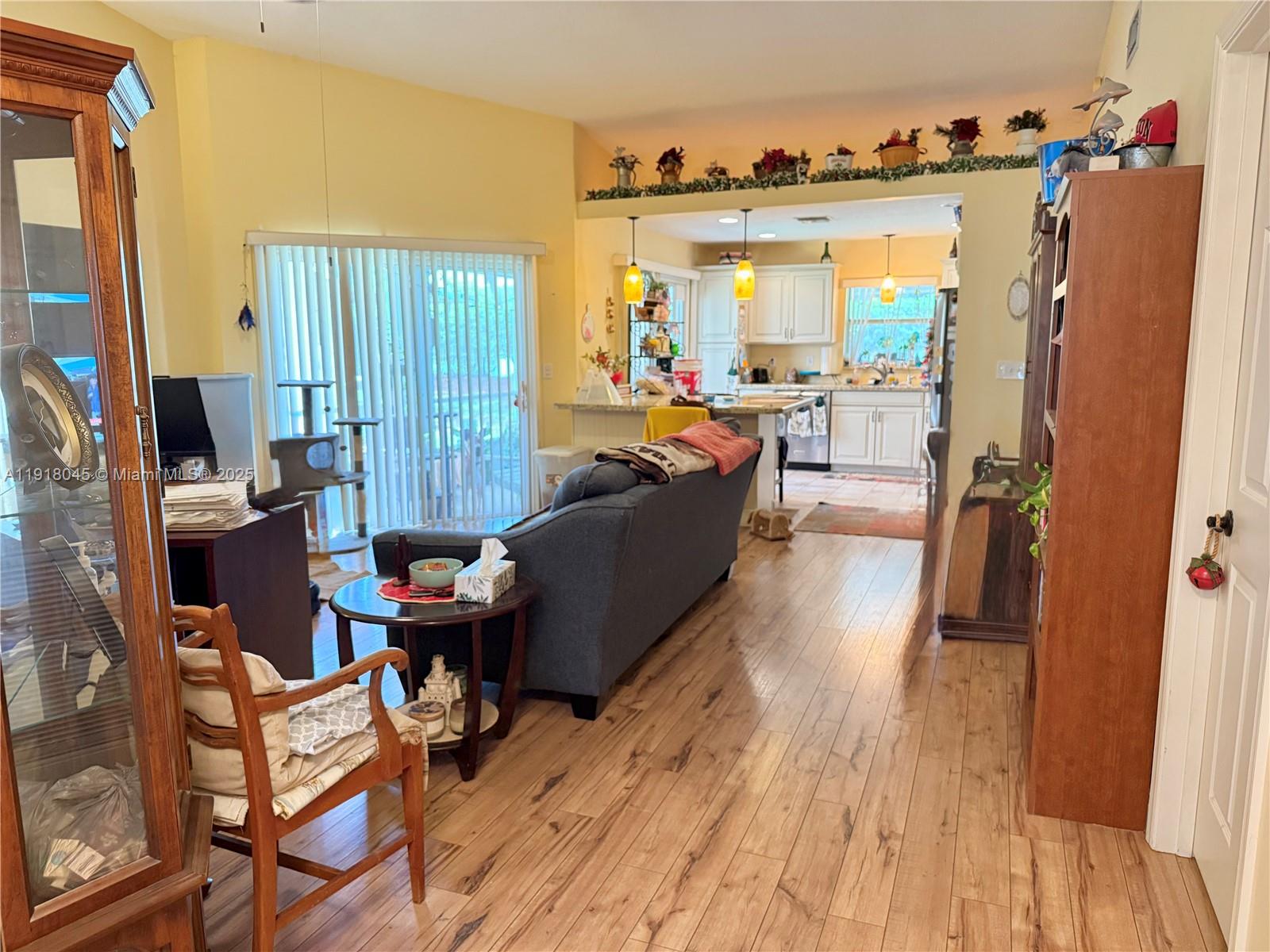 A living room with wood-look flooring opens into a kitchen with white cabinets — 737 SE 22nd Dr, Homestead FL 33033, HOMESTEAD, FL
