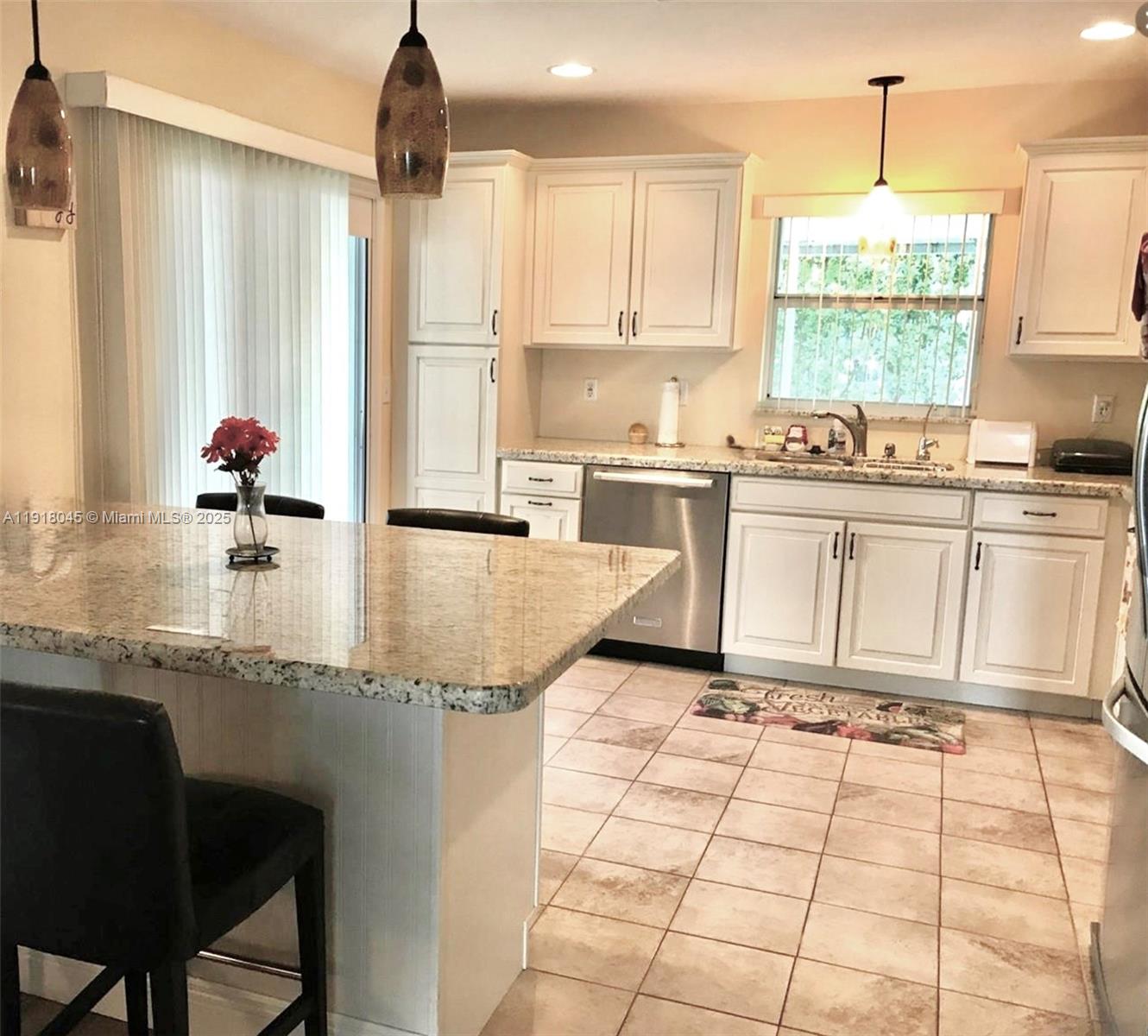 A kitchen features white cabinets, granite countertops, a central island, and tile flooring — 737 SE 22nd Dr, Homestead FL 33033, HOMESTEAD, FL