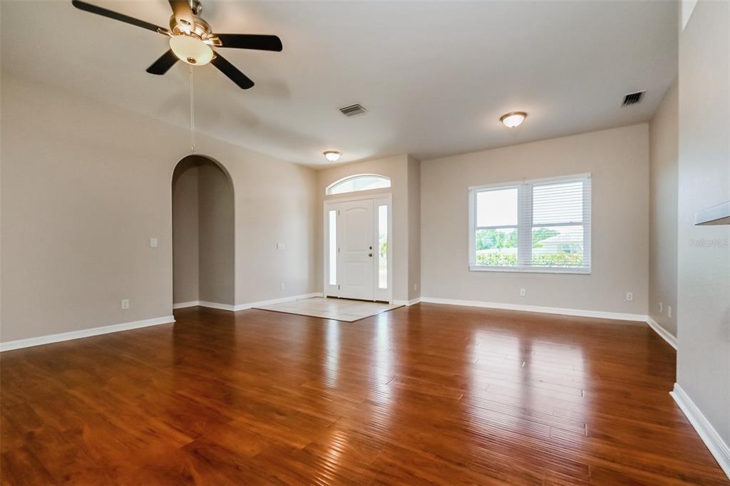 An empty living room features hardwood floors, a ceiling fan, and a front entryway — 4141 MERMELL CIRCLE, NORTH PORT, FL