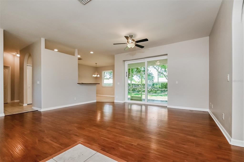 A living room with hardwood floors, a ceiling fan, and sliding glass doors to a patio — 4141 MERMELL CIRCLE, NORTH PORT, FL