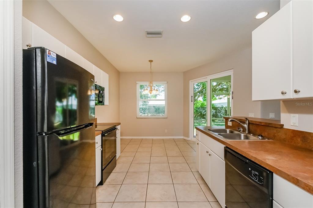 A kitchen features white cabinets, brown countertops, black appliances, and tile flooring — 4141 MERMELL CIRCLE, NORTH PORT, FL