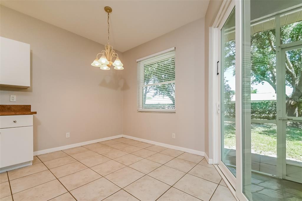 A dining area with tile floors, a hanging light fixture, and sliding glass doors — 4141 MERMELL CIRCLE, NORTH PORT, FL