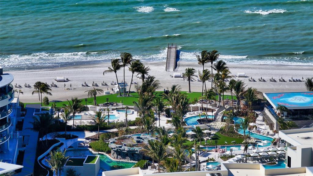An aerial view of a beachfront resort featuring multiple swimming pools, palm trees, and sand — 1591 GULF OF MEXICO DRIVE UNIT 313, LONGBOAT KEY, FL