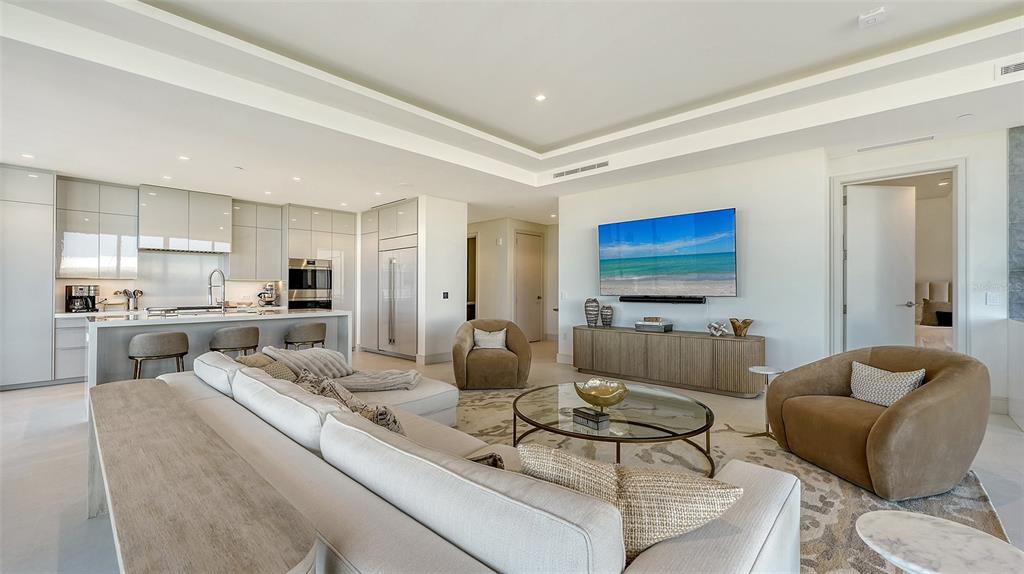 A modern open-concept living room features a kitchen with gray cabinets and a large sofa — 1591 GULF OF MEXICO DRIVE UNIT 313, LONGBOAT KEY, FL