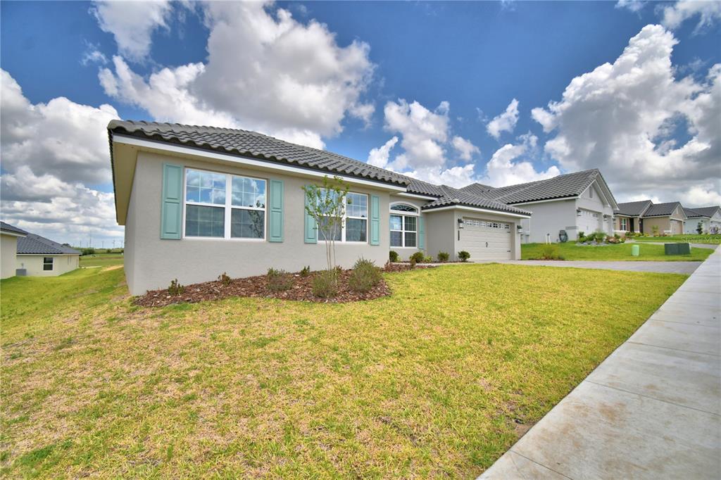 A single-story house with a gray stucco exterior, tile roof, and light blue shutters — 4270 JULIANA LAKE DRIVE, AUBURNDALE, FL