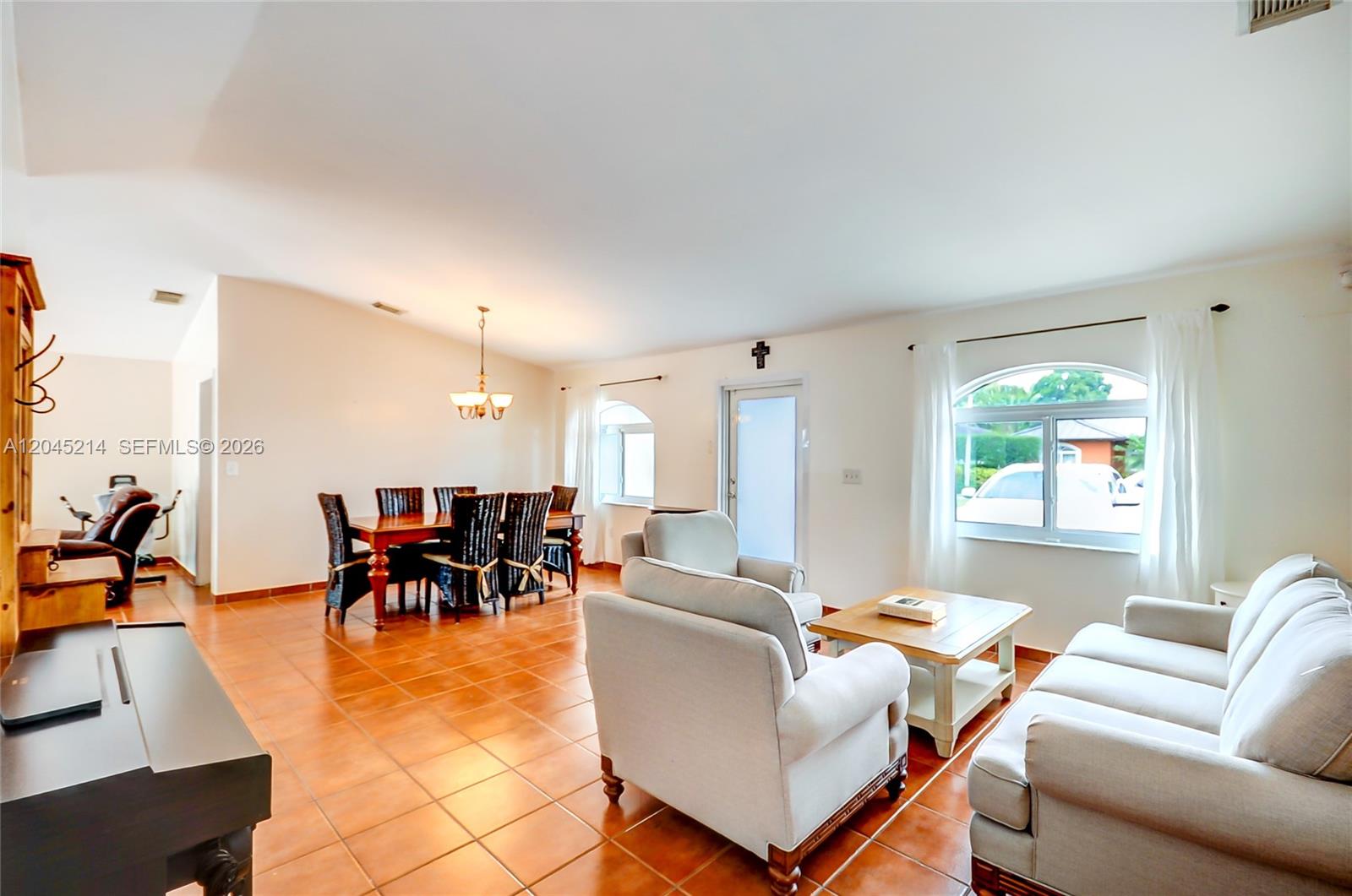 A spacious living and dining area features terracotta tile flooring and white walls — 14368 SW 165th St, Miami FL 33177, MIAMI, FL
