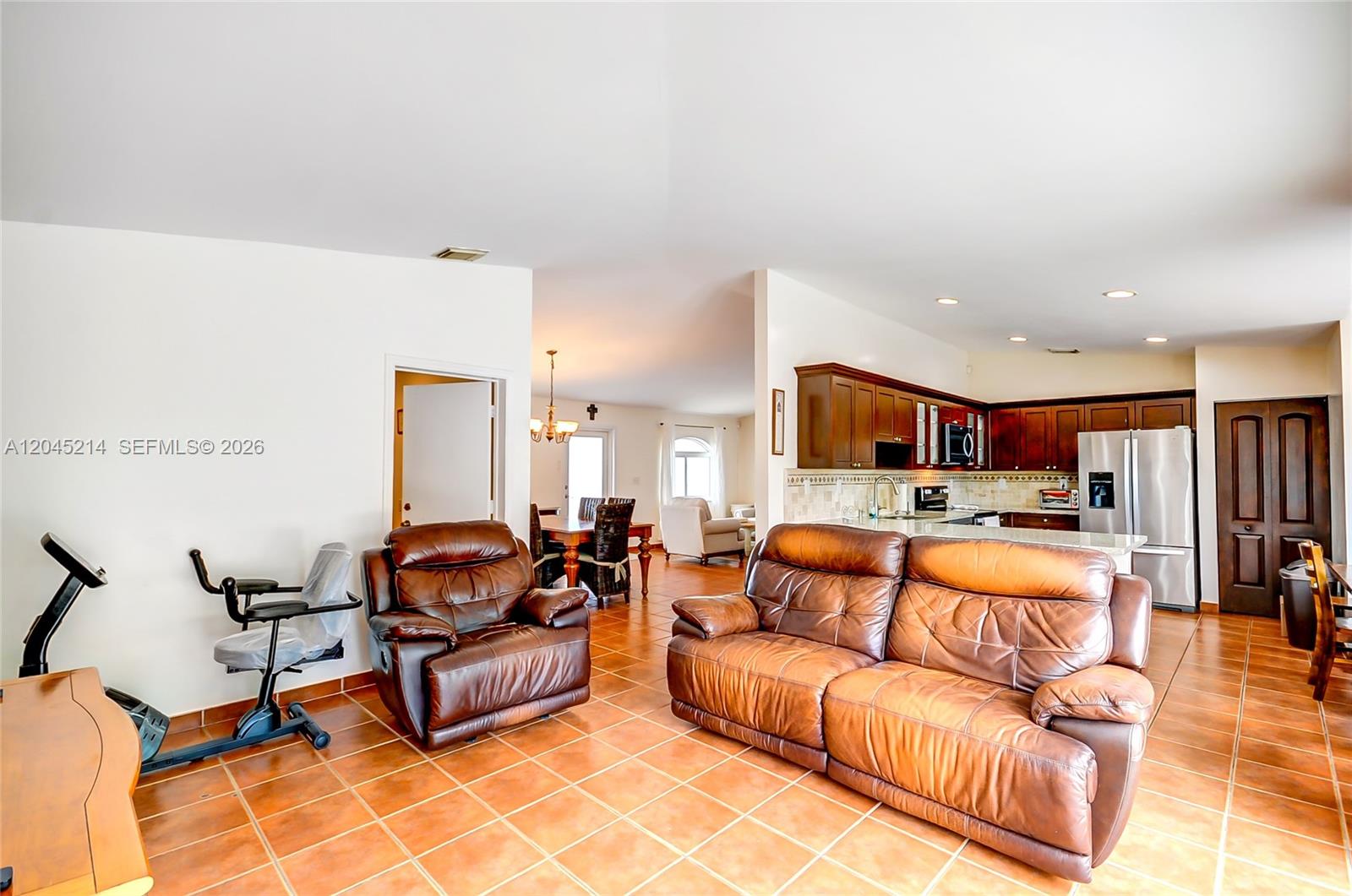An open-concept living area features brown leather furniture, tile flooring, and an adjacent kitchen — 14368 SW 165th St, Miami FL 33177, MIAMI, FL