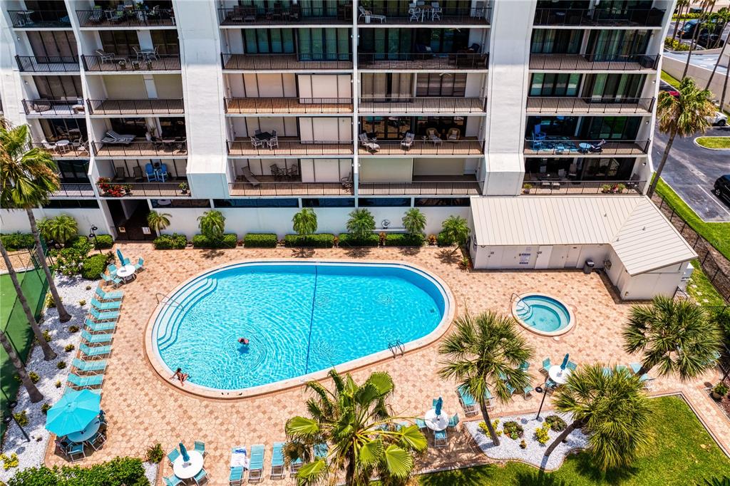 An aerial view shows a multi-story apartment building with a swimming pool and hot tub — 1250 GULF BOULEVARD UNIT 302, CLEARWATER BEACH, FL