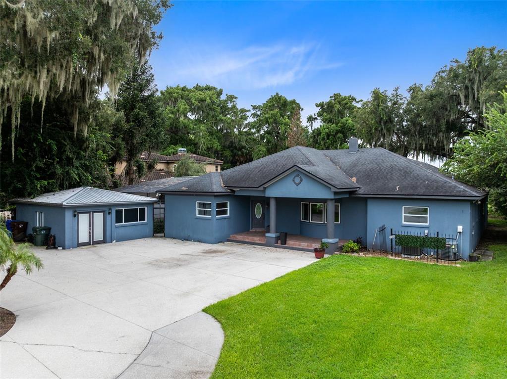 A blue single-story house with a detached garage and a large concrete driveway — 807 NEPTUNE ROAD, KISSIMMEE, FL