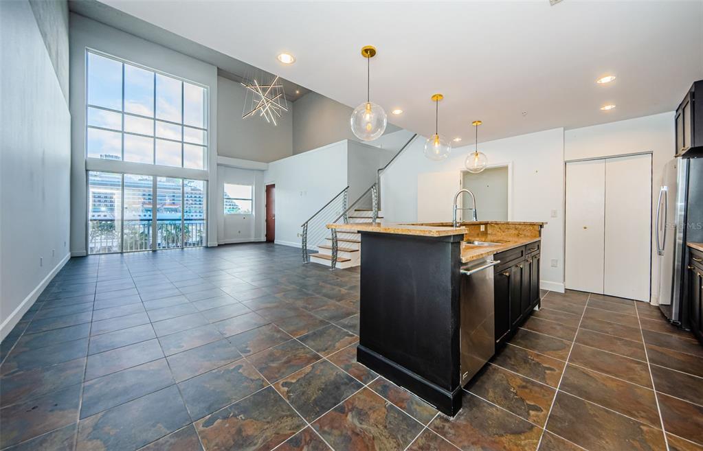 An open-concept kitchen and living area features high ceilings, tile flooring, and a staircase — 1002 CHANNELSIDE DRIVE UNIT 3C, TAMPA, FL