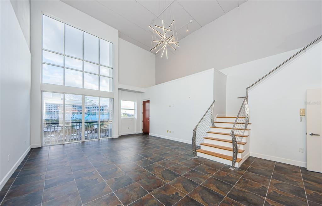 A modern living room features high ceilings, tile flooring, a staircase, and floor-to-ceiling windows — 1002 CHANNELSIDE DRIVE UNIT 3C, TAMPA, FL