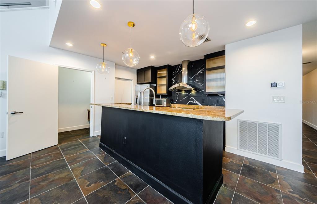 A kitchen features a black island, granite countertops, and a black marble-patterned backsplash — 1002 CHANNELSIDE DRIVE UNIT 3C, TAMPA, FL