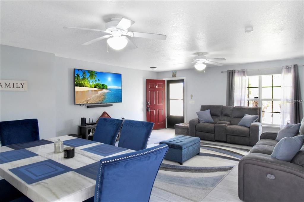 A living and dining area features blue furniture, a television, and two ceiling fans — 15427 WINTER BREEZE LANE, WIMAUMA, FL