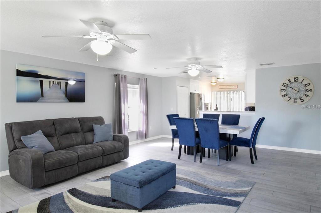 A living and dining area features a gray sofa, blue ottoman, and blue dining chairs — 15427 WINTER BREEZE LANE, WIMAUMA, FL