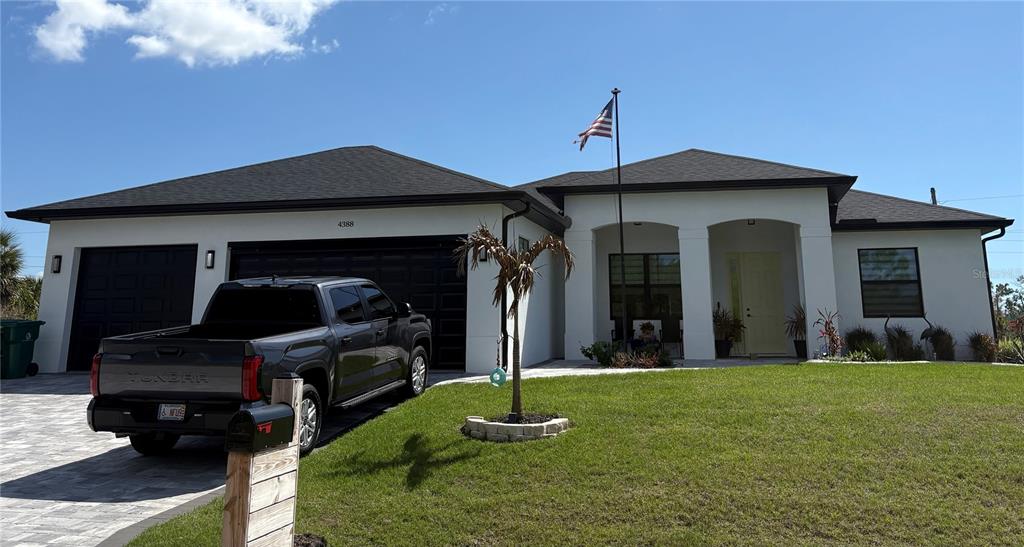A single-story house with a white exterior, dark roof, three-car garage, and a parked truck — 7194 PINEDALE DRIVE, PORT CHARLOTTE, FL