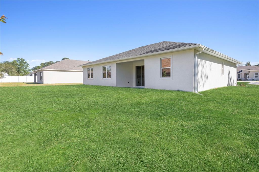The exterior of a beige stucco house features a covered patio and a large lawn — 789 W HALLAM DR, DUNNELLON, FL