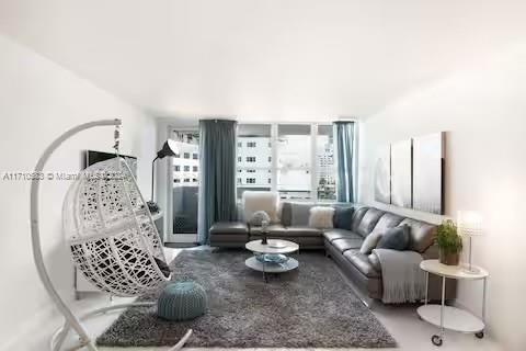 A living room features a white hanging chair, a gray sectional sofa, and a rug — 100 Lincoln Rd # 739, Miami Beach FL 33139, MIAMI BEACH, FL