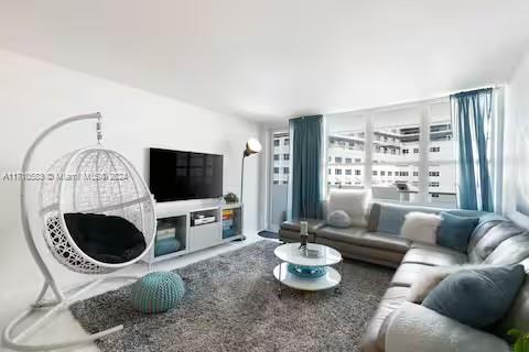 A living room features a hanging chair, a gray sectional sofa, and a television console — 100 Lincoln Rd # 739, Miami Beach FL 33139, MIAMI BEACH, FL