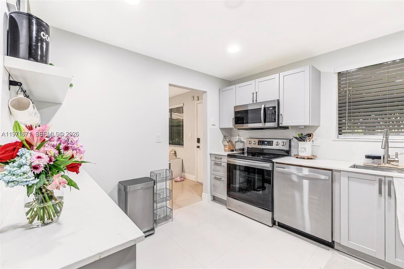 A kitchen features light gray cabinets, stainless steel appliances, and a white countertop — 601 Ives Dairy Rd # 00, Miami FL 33179, MIAMI, FL